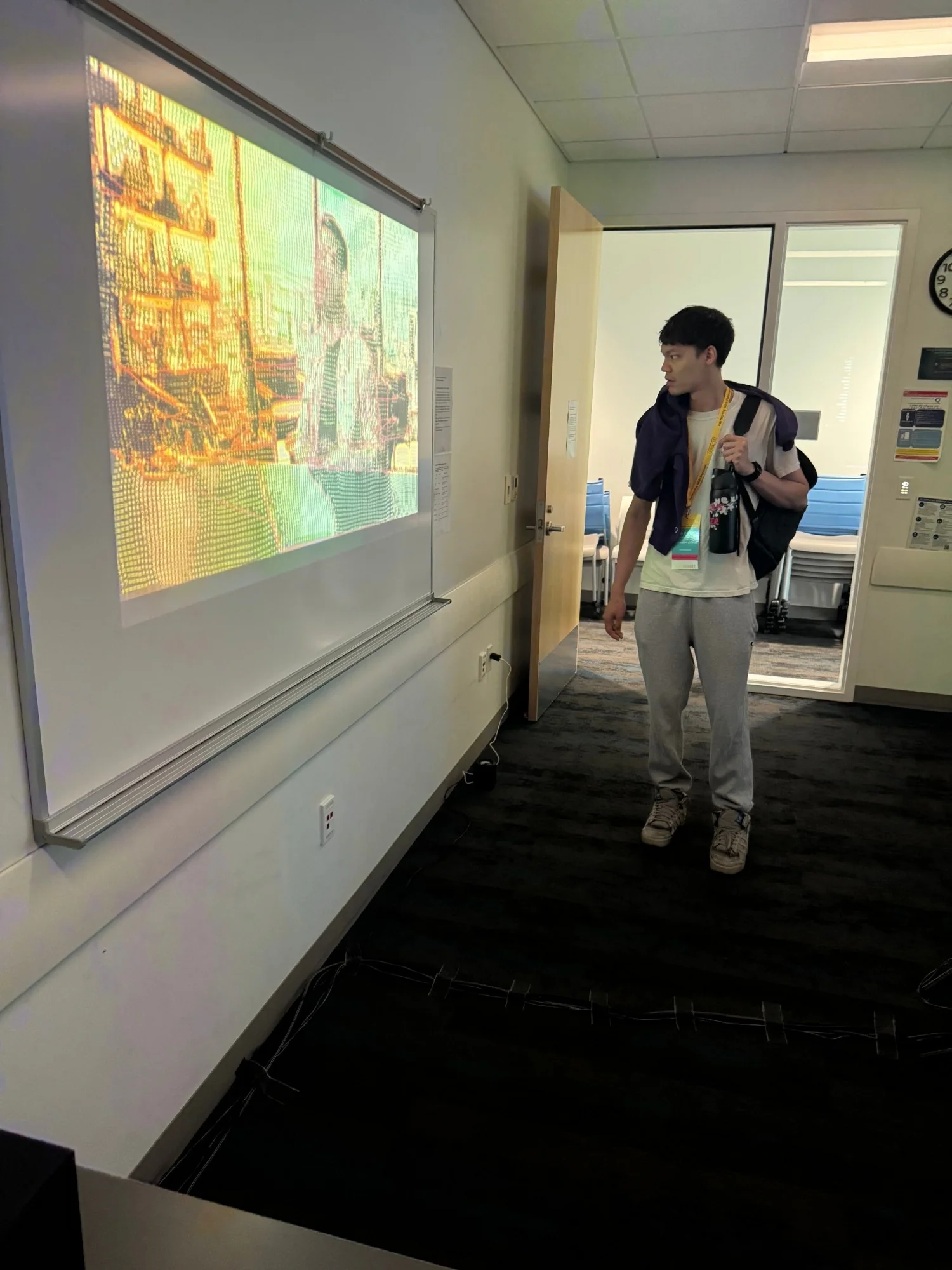 A visitor stops at the door to watch the projection, the frame rendered as a field of characters